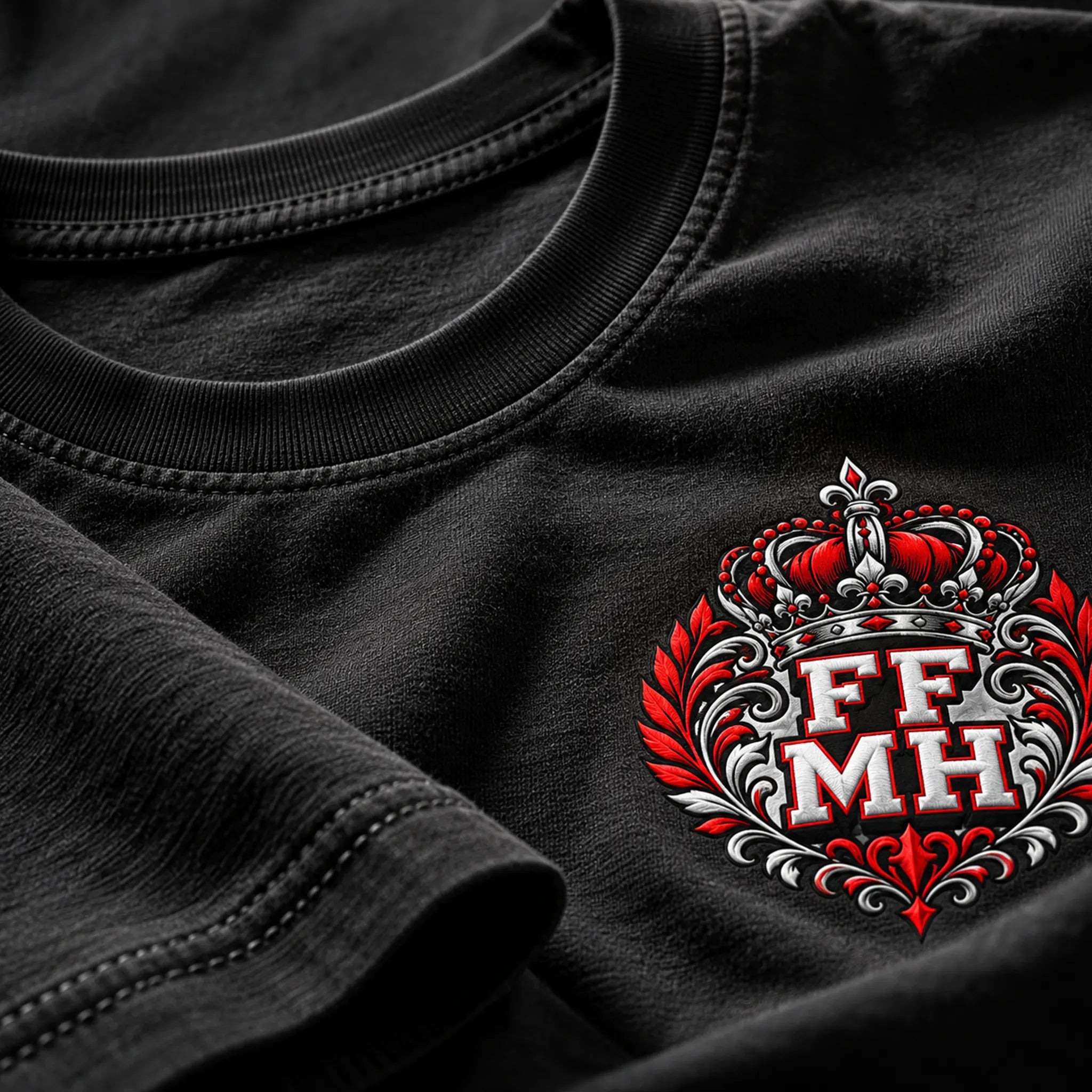 Close-up of a black crewneck t-shirt featuring a red, white, and silver graphic crest with the letters 'FF MH' on the chest.