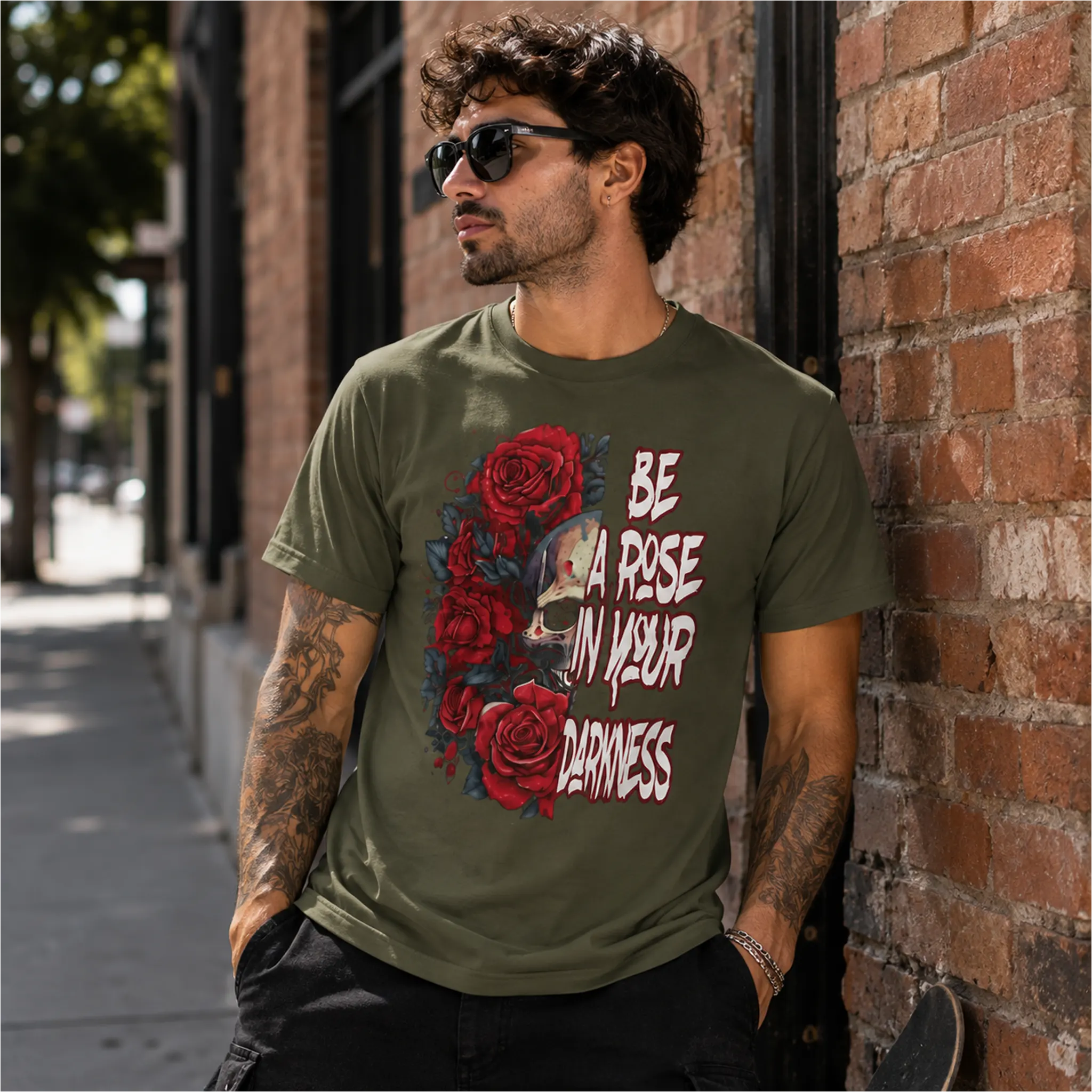 Man wearing Be A Rose In Your Darkness Military Green graphic tee with skull and red roses design in an urban setting – Black Heart Tees motivational apparel