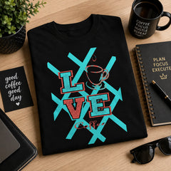 Love Coffee black graphic tee styled with coffee mug, notebook and plant on a modern workspace – Black Heart Tees motivational apparel