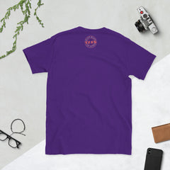 Purple t-shirt with a Black Heart logo on the back, placed on a light gray surface with a camera and glasses around.