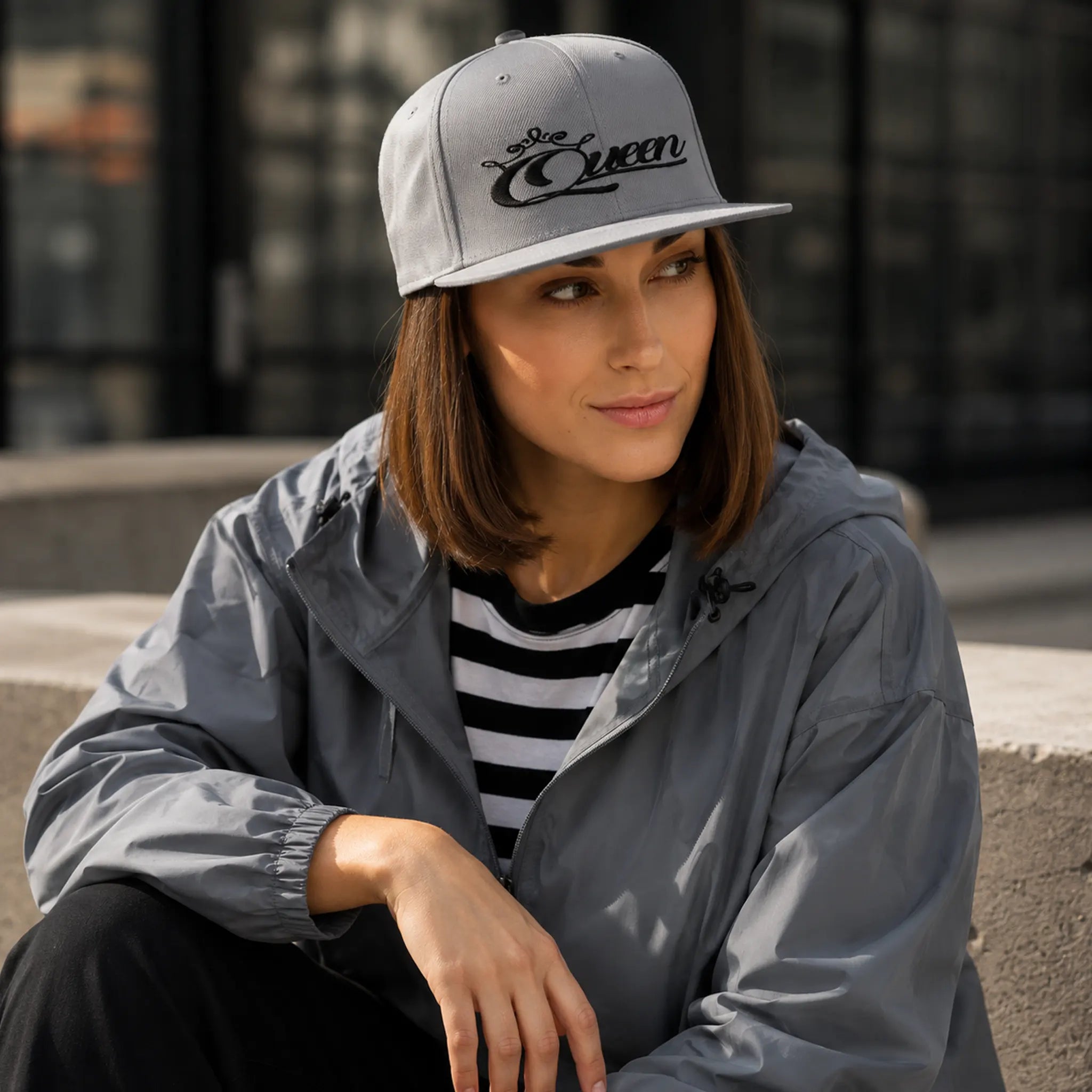 Woman wearing a stylish gray snapback hat with "Queen" design – part of the motivational hats collection at Black Heart Tees Clothing.
