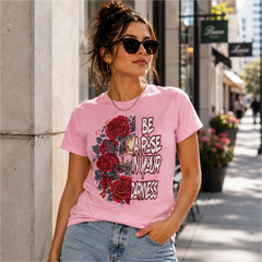 Woman wearing Be A Rose In Your Darkness pink graphic tee with skull and red roses design in an urban shopping district – Black Heart Tees motivational apparel