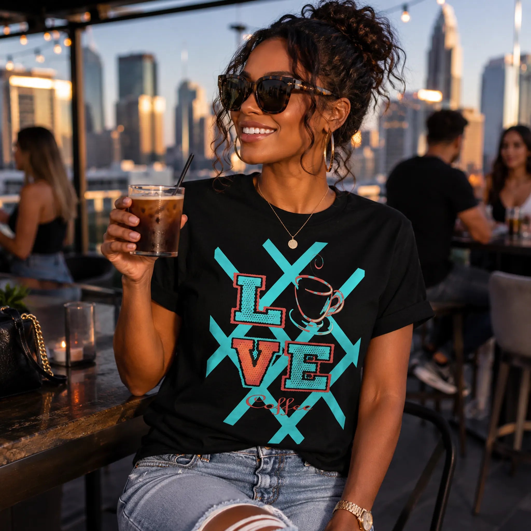 Woman wearing Love Coffee black graphic tee holding iced coffee at a rooftop gathering – Black Heart Tees motivational apparel