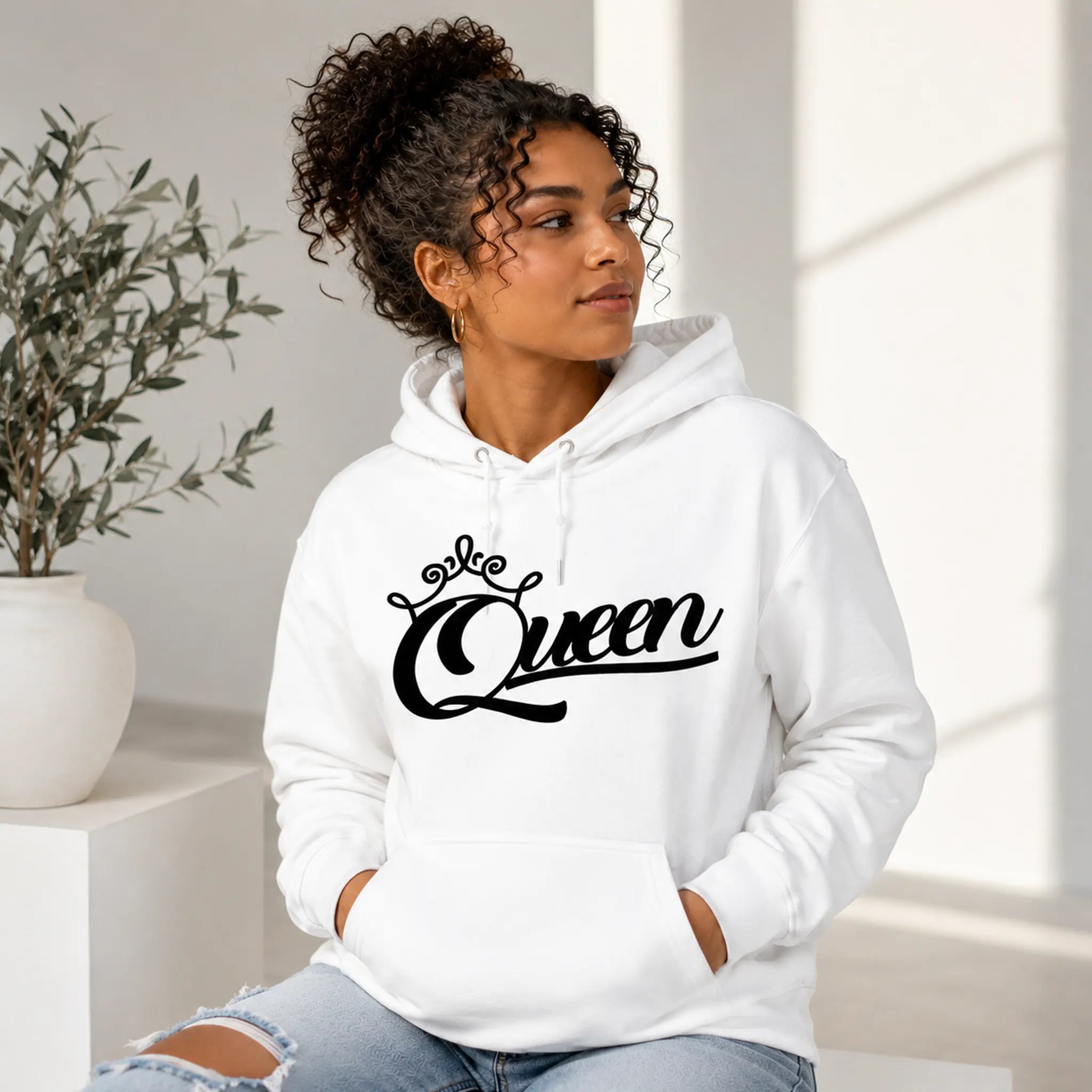 Woman wearing Queen white pullover hoodie with black crown script design in a clean minimal lifestyle setting – Black Heart Tees motivational apparel.